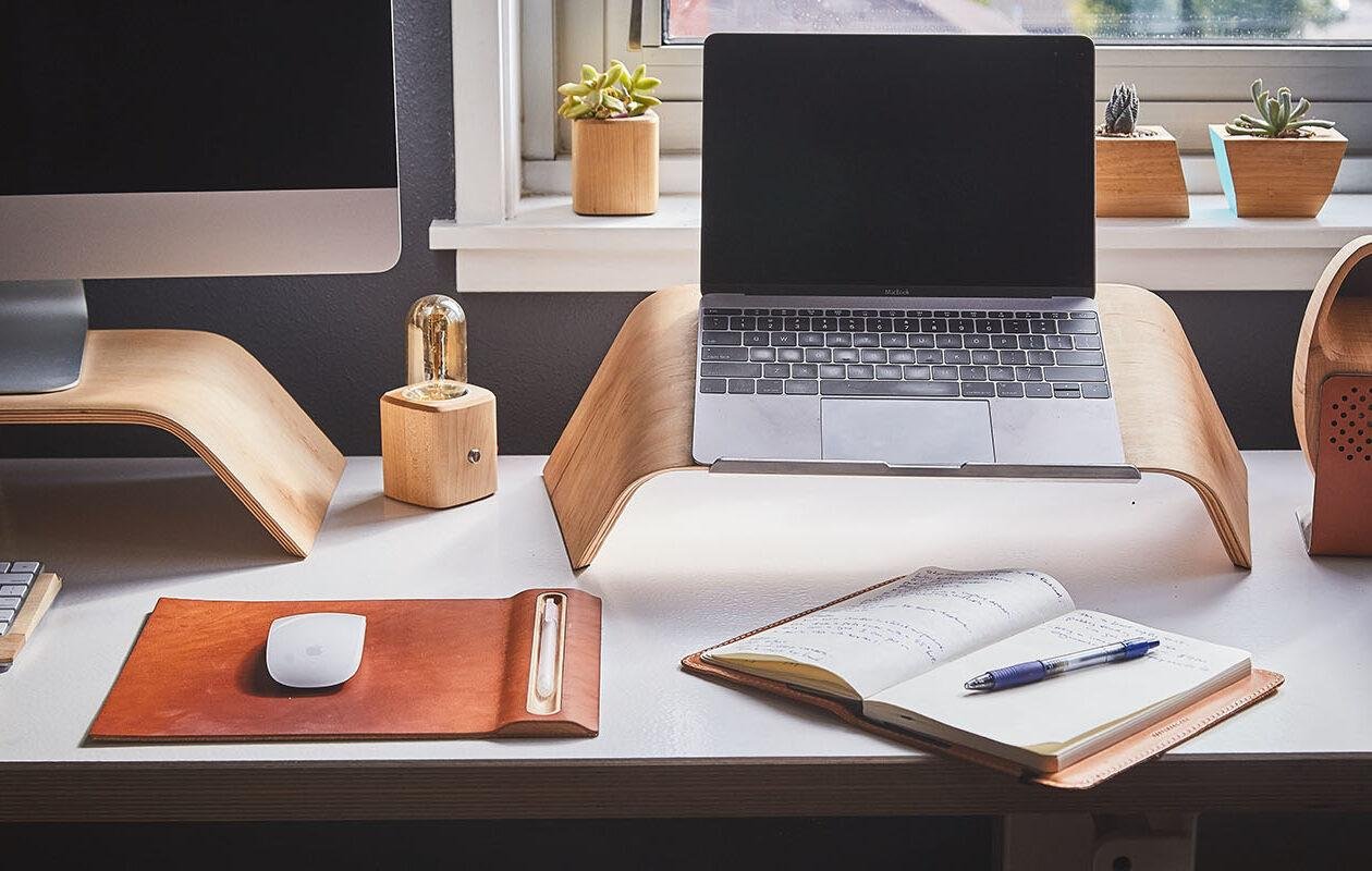 Deep clean office in London with a MacBook on a laptop table and with an open diary with pen on it and some other decorative stuff
