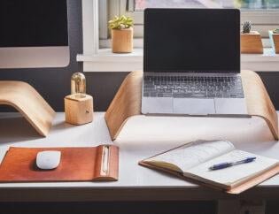 Deep clean office in London with a MacBook on a laptop table and with an open diary with pen on it and some other decorative stuff