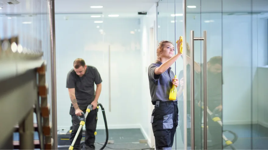 Professional cleaner using eco-friendly products and squeegee to clean office windows in London commercial building
