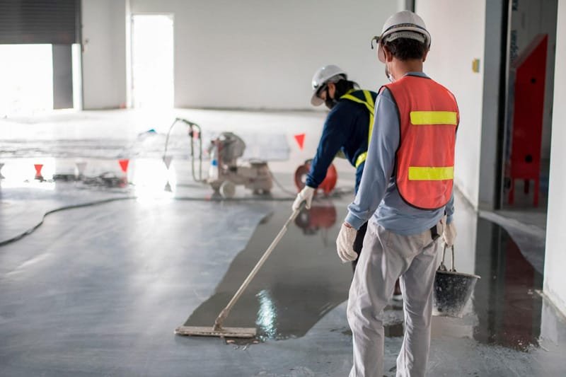 Commercial Post-Construction Cleaning Portsmouth - Professional Crew Construction cleaning crew in high-visibility safety vests using specialized equipment to clean concrete floors in commercial building renovation