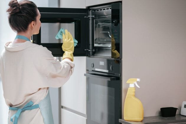 Affordable Oven Cleaning Portsmouth - Eco-Friendly Professional Service Professional oven cleaner in protective gear wiping down built-in oven interior using eco-friendly cleaning products in Portsmouth kitchen