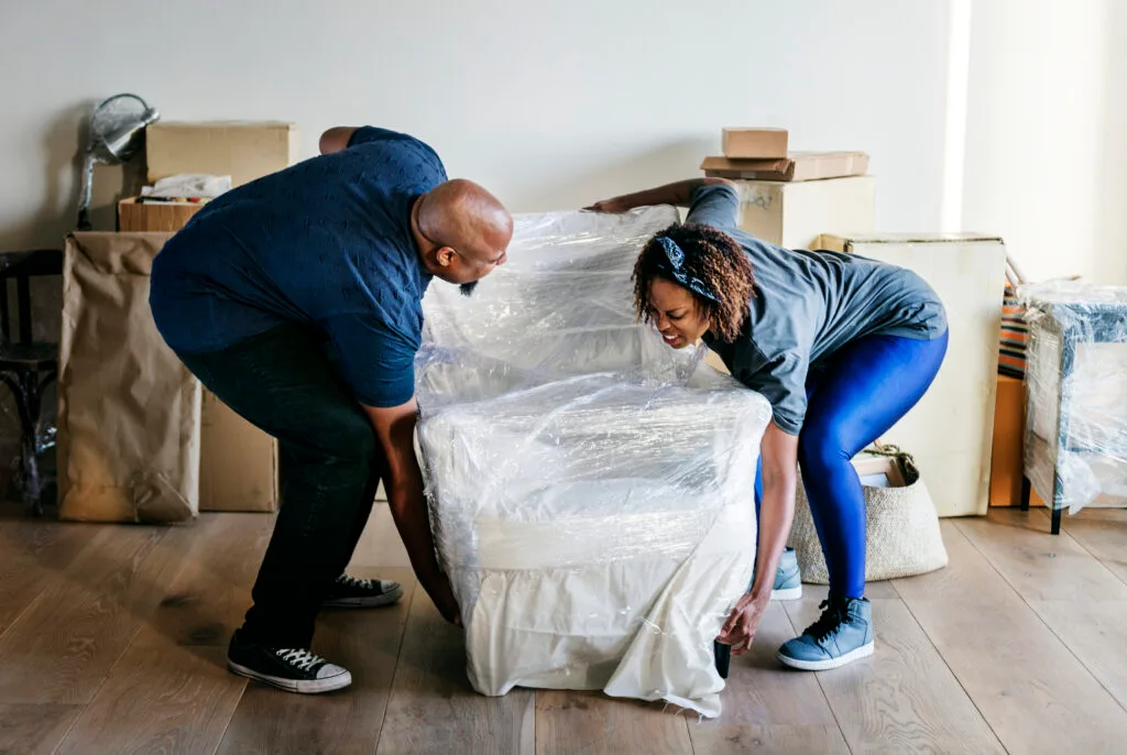 Couple packing furniture with protective wrap during house move in Southampton preparing for professional move out cleaning service