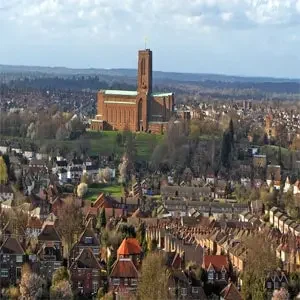 Aerial view of the historic town of Guildford, England, featuring the iconic Guildford Cathedral spire rising above the quaint rooftops and surrounding countryside.